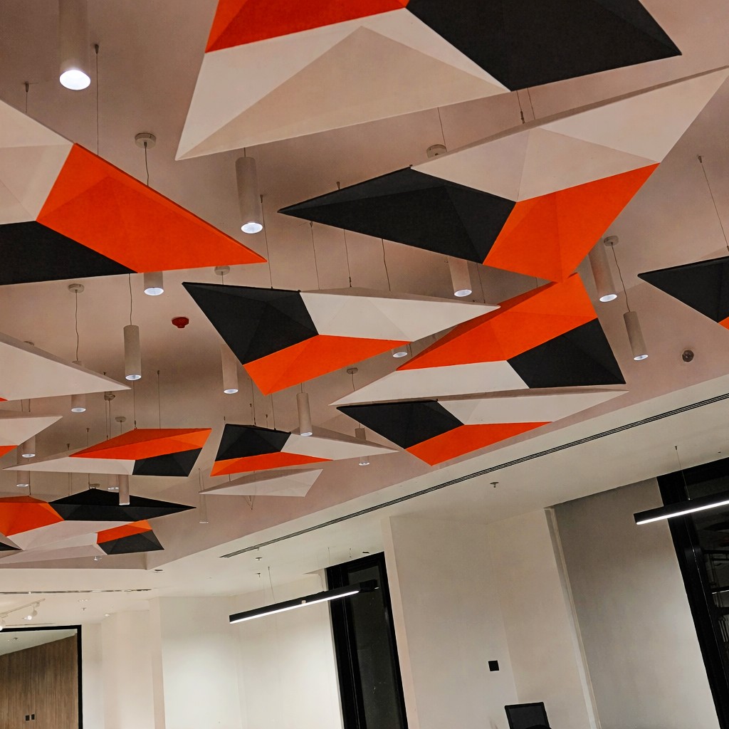 Geometric acoustic ceiling clouds suspended in a modern commercial office interior to improve sound absorption and visual design.